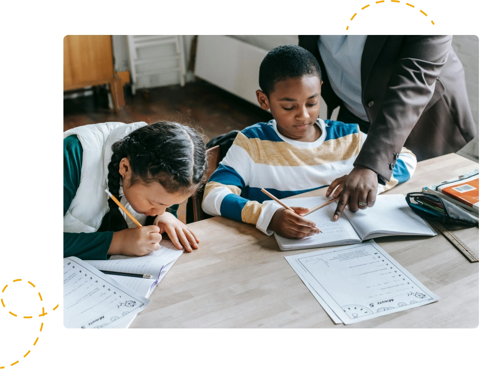 Two children are writing on paper while a man helps them.