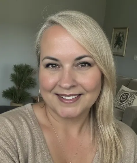 A woman with blonde hair and wearing a beige shirt.